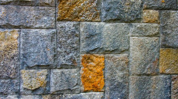 Detailed view of a textured stone wall showcasing varying colors and rough surfaces.