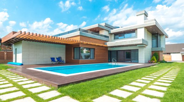 Contemporary house with pool, lush lawn, and clear skies.